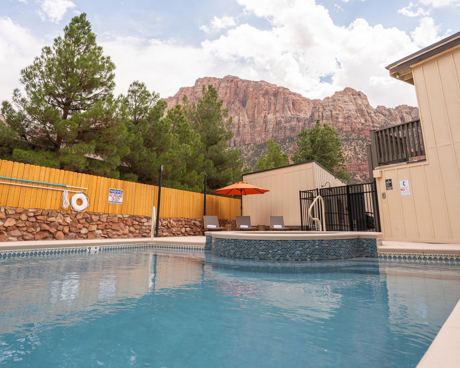 Swimming pool with red rock mountains visible in the background at sunset.