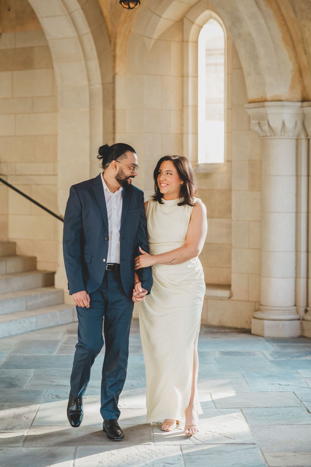 A couple shares a romantic moment in a light-filled stone hallway at the Washington National Cathedral