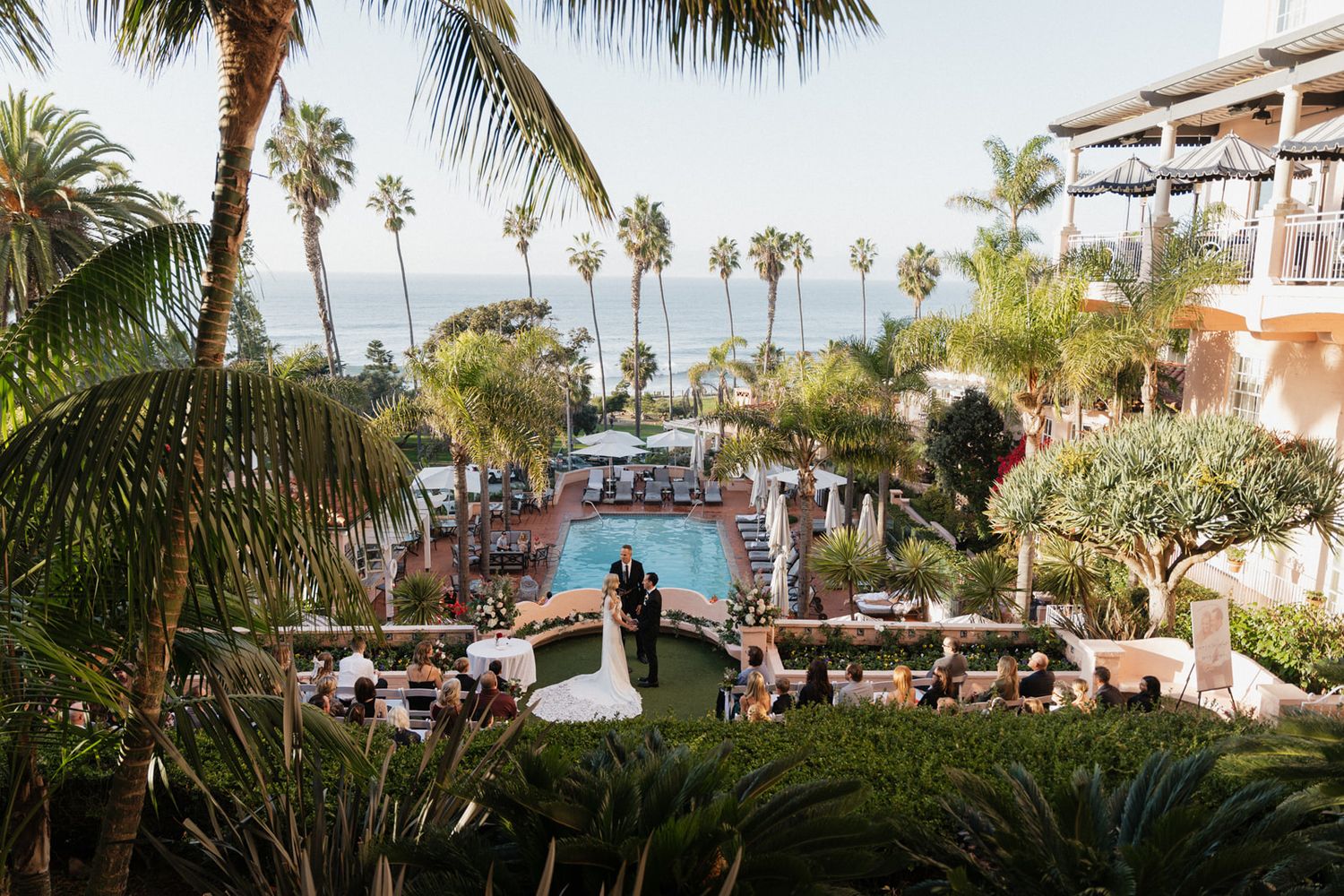Scenic panoramic view of a tropical resort with palm trees, swimming pools, and beachfront buildings in Hawaii.