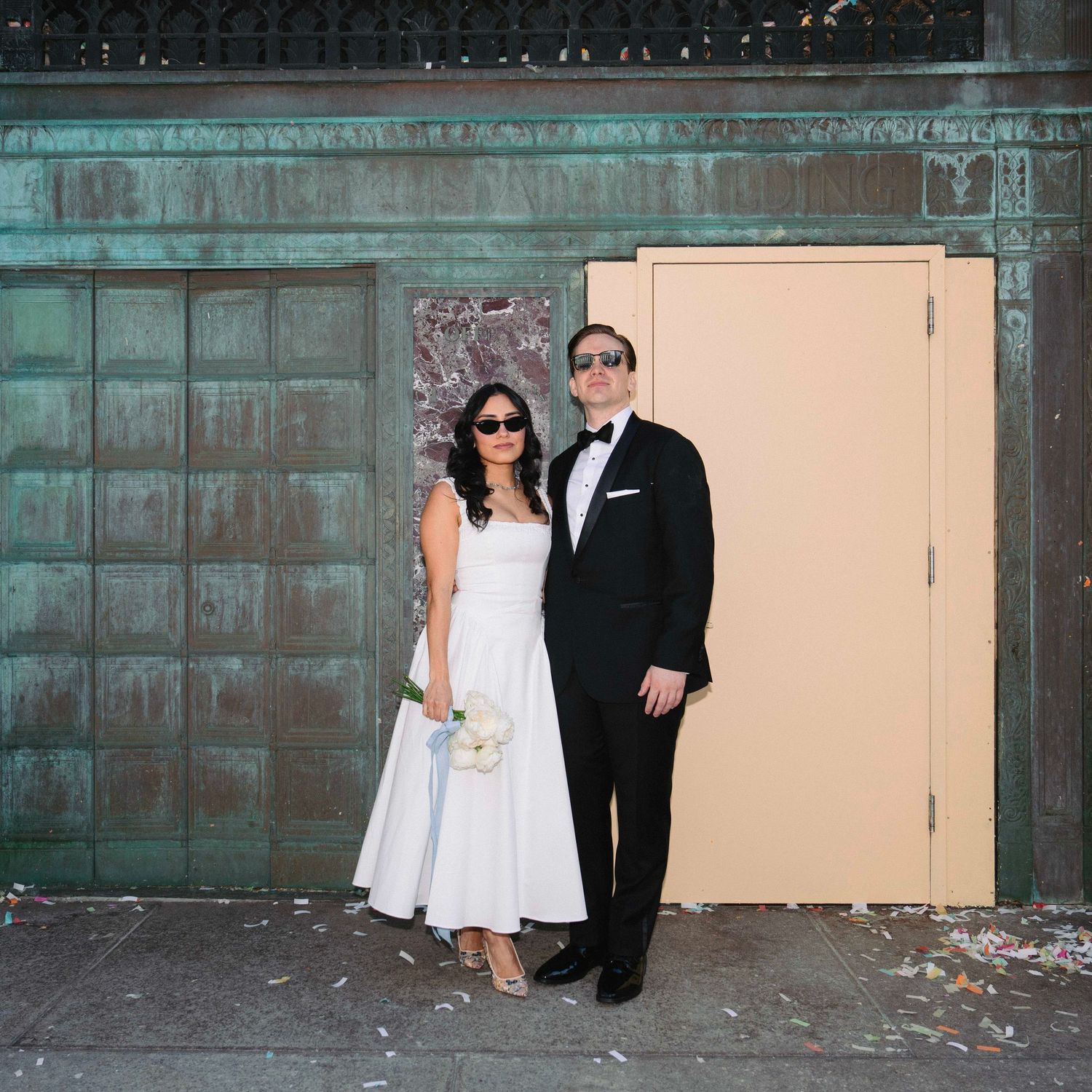 Wedding couple posing for portraits against an industrial backdrop with peach colored walls.