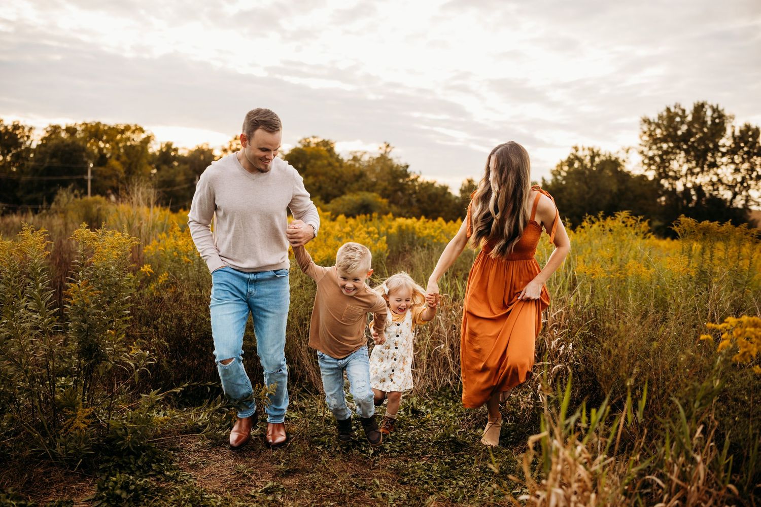 Family enjoying a spring photo session in a park with colorful autumn foliage and a white gazebo in the background.