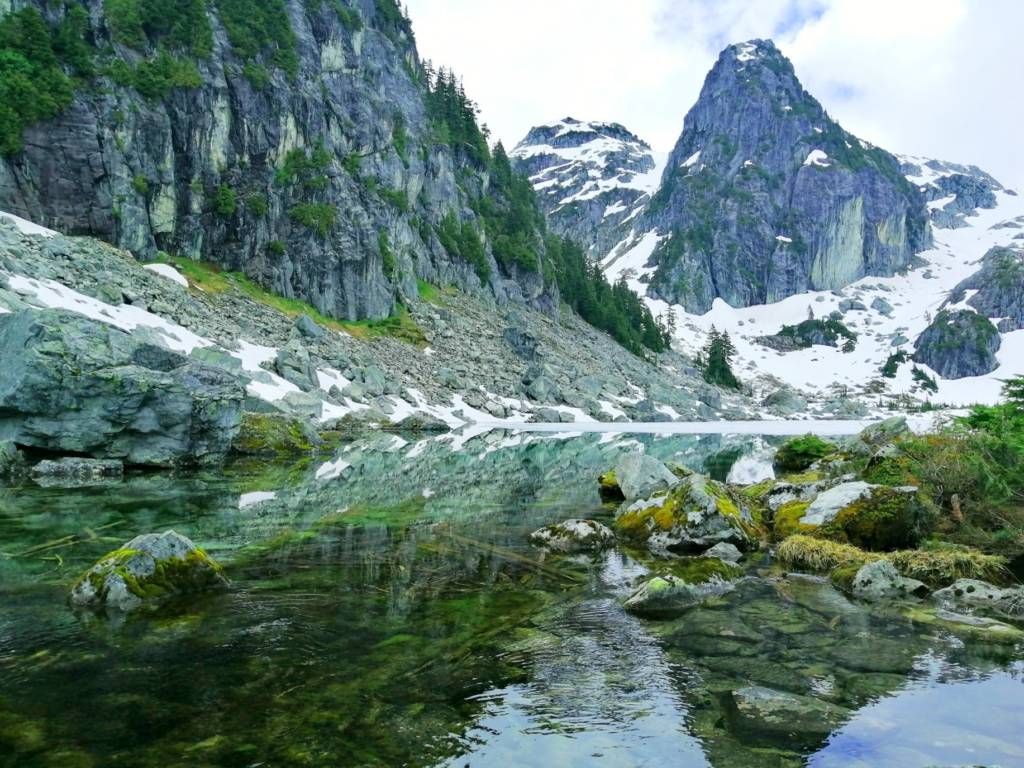 The rocky Watersprite Lake in BC in the foreground with an alpine summit in the background