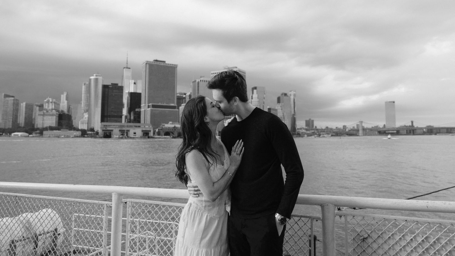 Romantic waterfront engagement session with city skyline in the background.