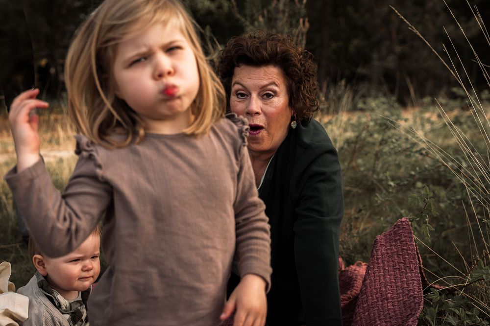 Family members embrace and share tender moments together in a natural outdoor setting during golden hour.