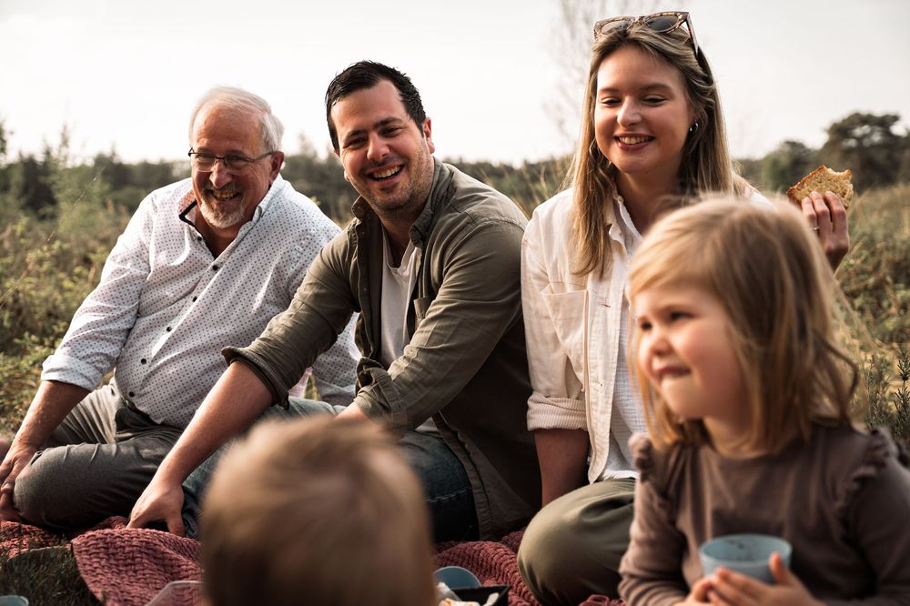 A group of people laughing and enjoying a casual outdoor gathering together on a sunny day.