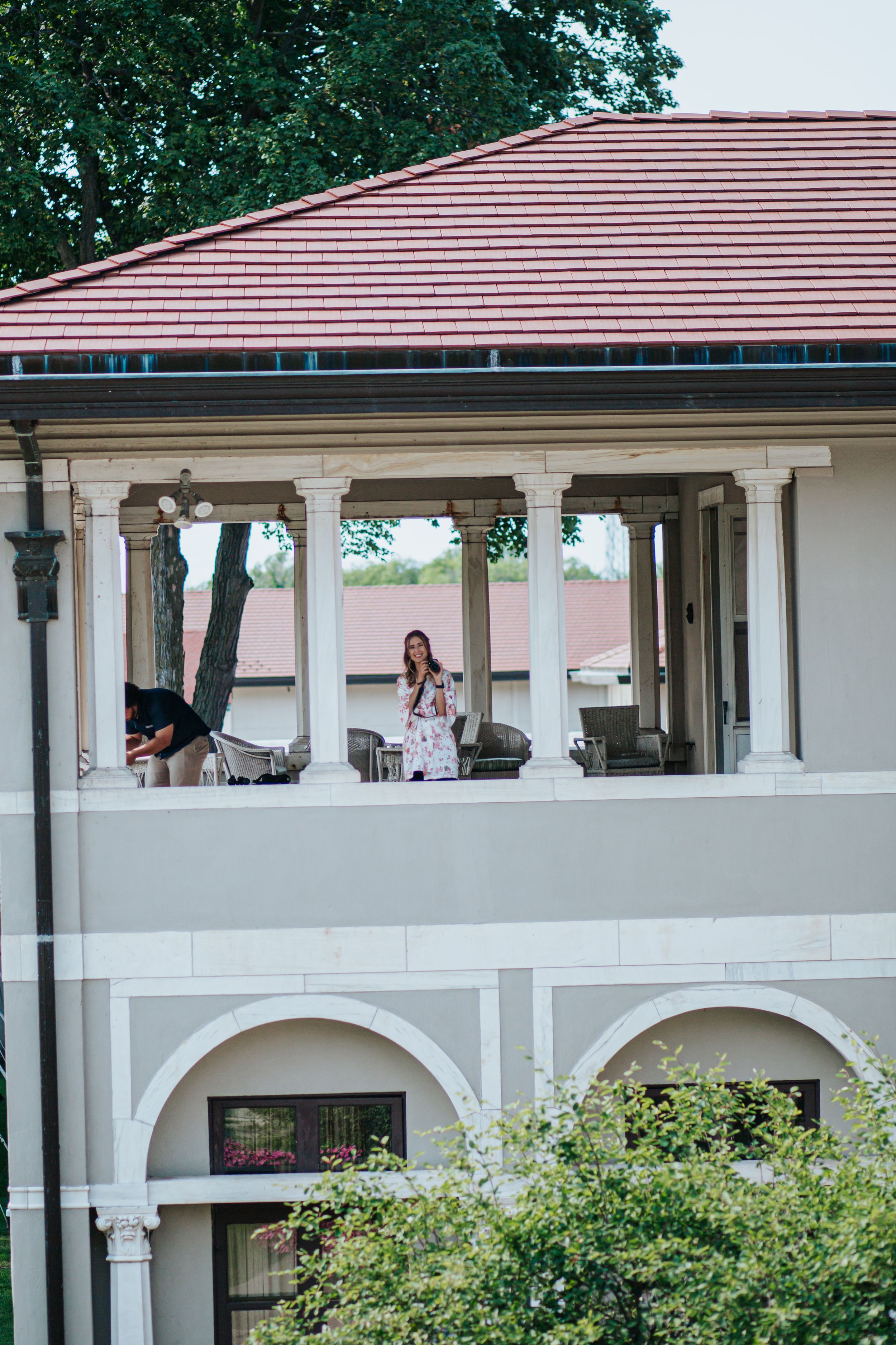 White stucco building with arched openings and red tile roof features Mediterranean-style architecture and lush landscaping.