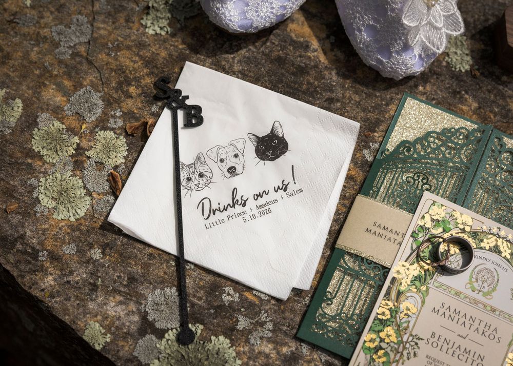 Custom wedding cocktail napkins with pet portraits and personalized details beside rings and stationery.