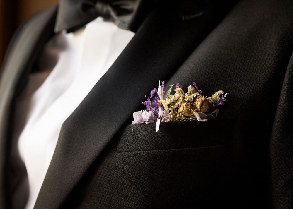 Close-up of a black tuxedo lapel adorned with a decorative purple and gold floral pocket square.