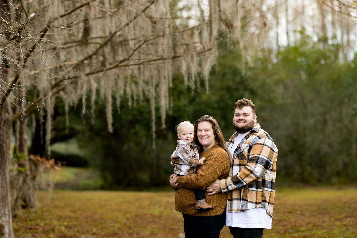 A family shares tender moments together in a wooded outdoor setting during an autumn photo session.