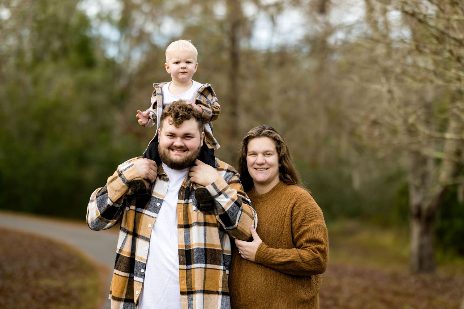 A family in coordinating fall outfits smiles together during an outdoor autumn photoshoot.