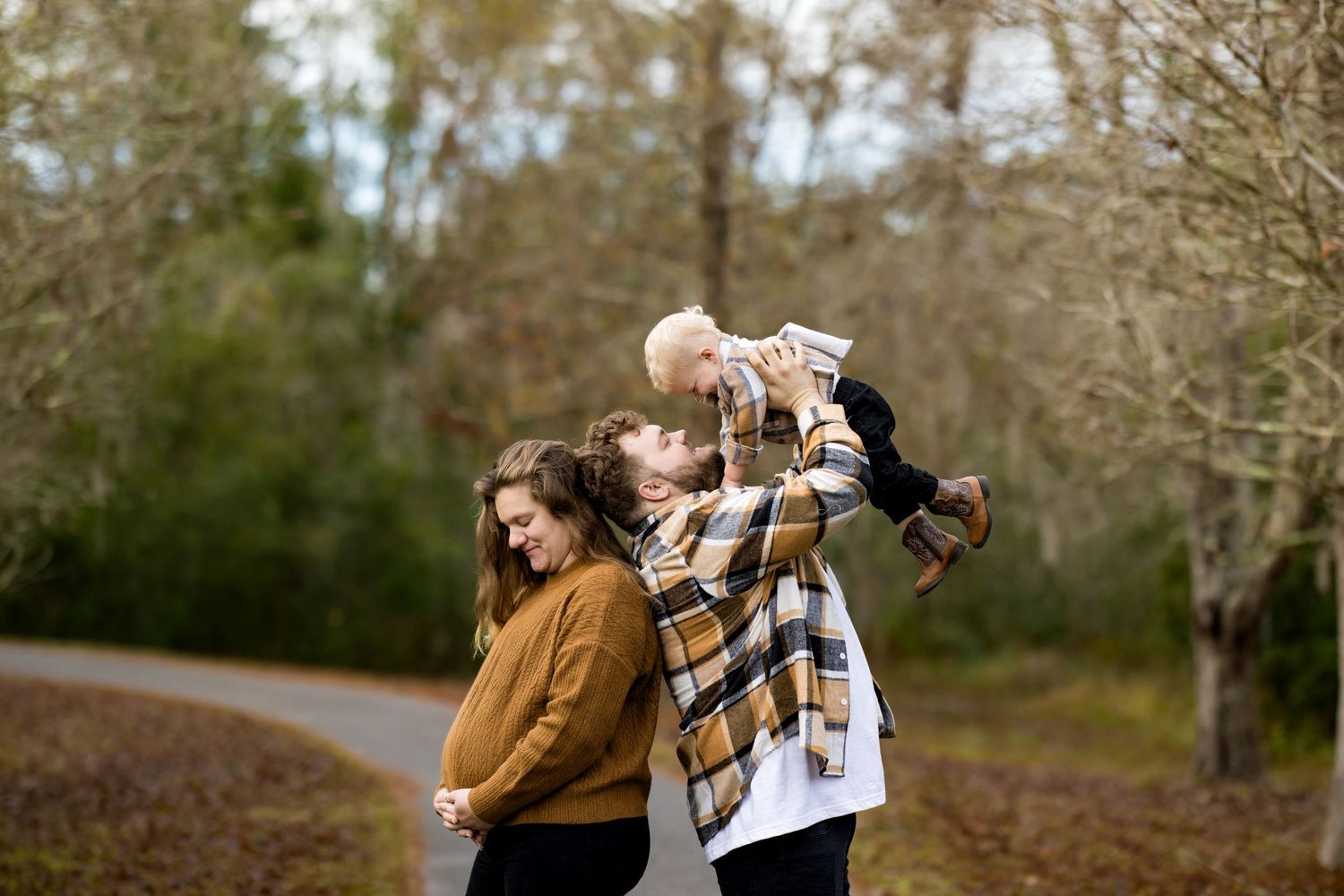 A couple embraces while walking together on a wooded trail during autumn.