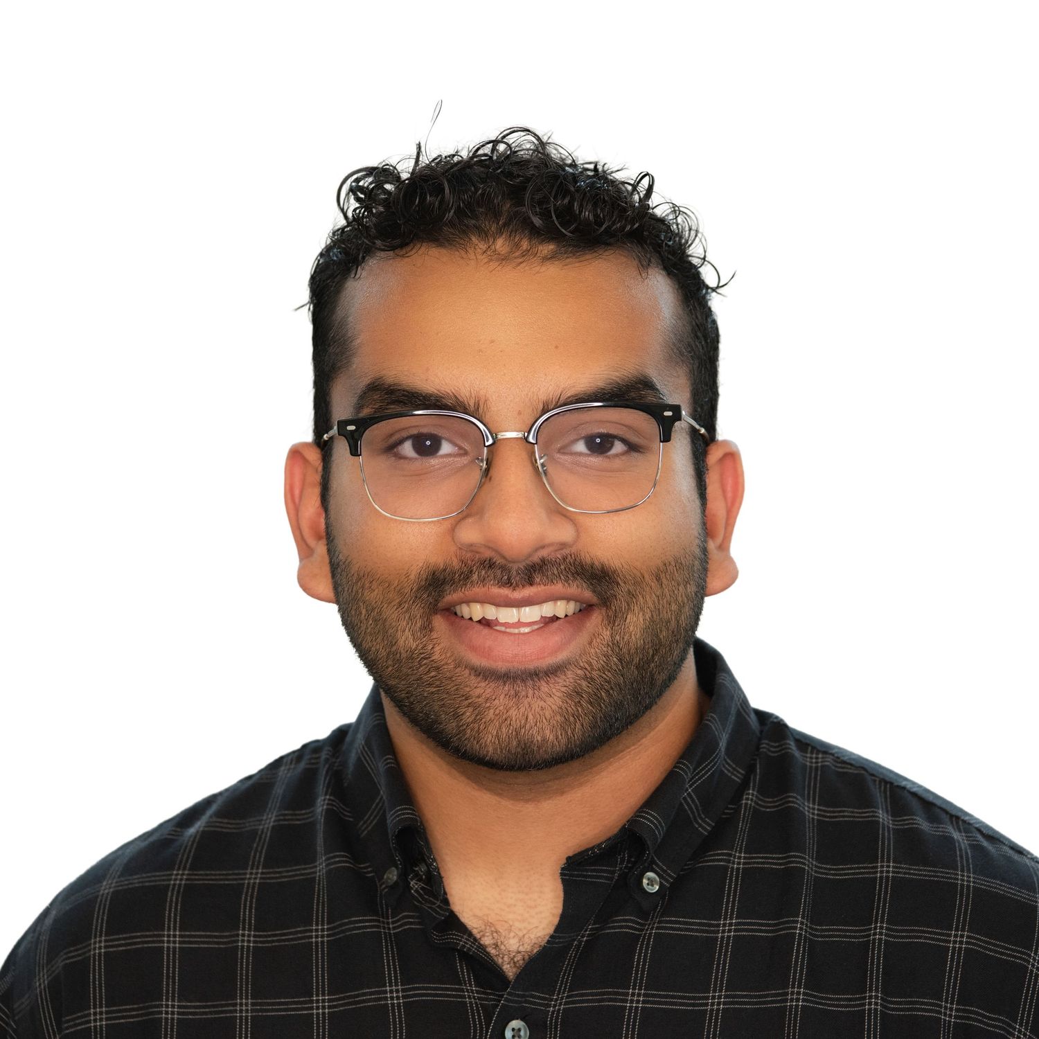 A smiling person wearing glasses and a black plaid shirt poses in a headshot against a white background.