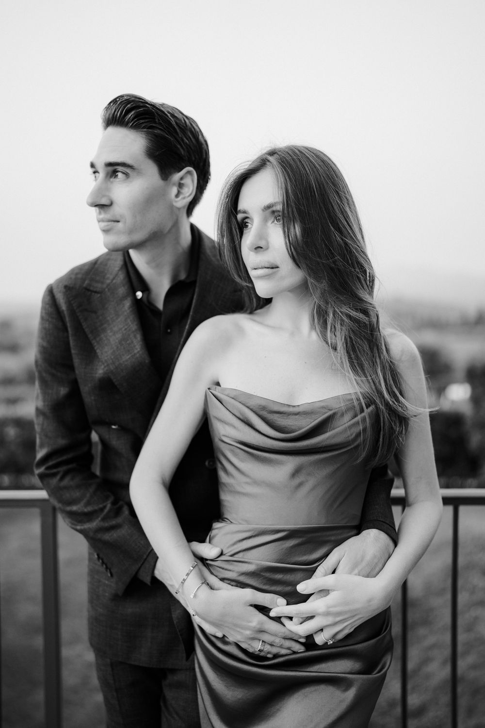 A romantic black and white photo series showing a couple embracing on a balcony in elegant evening attire.