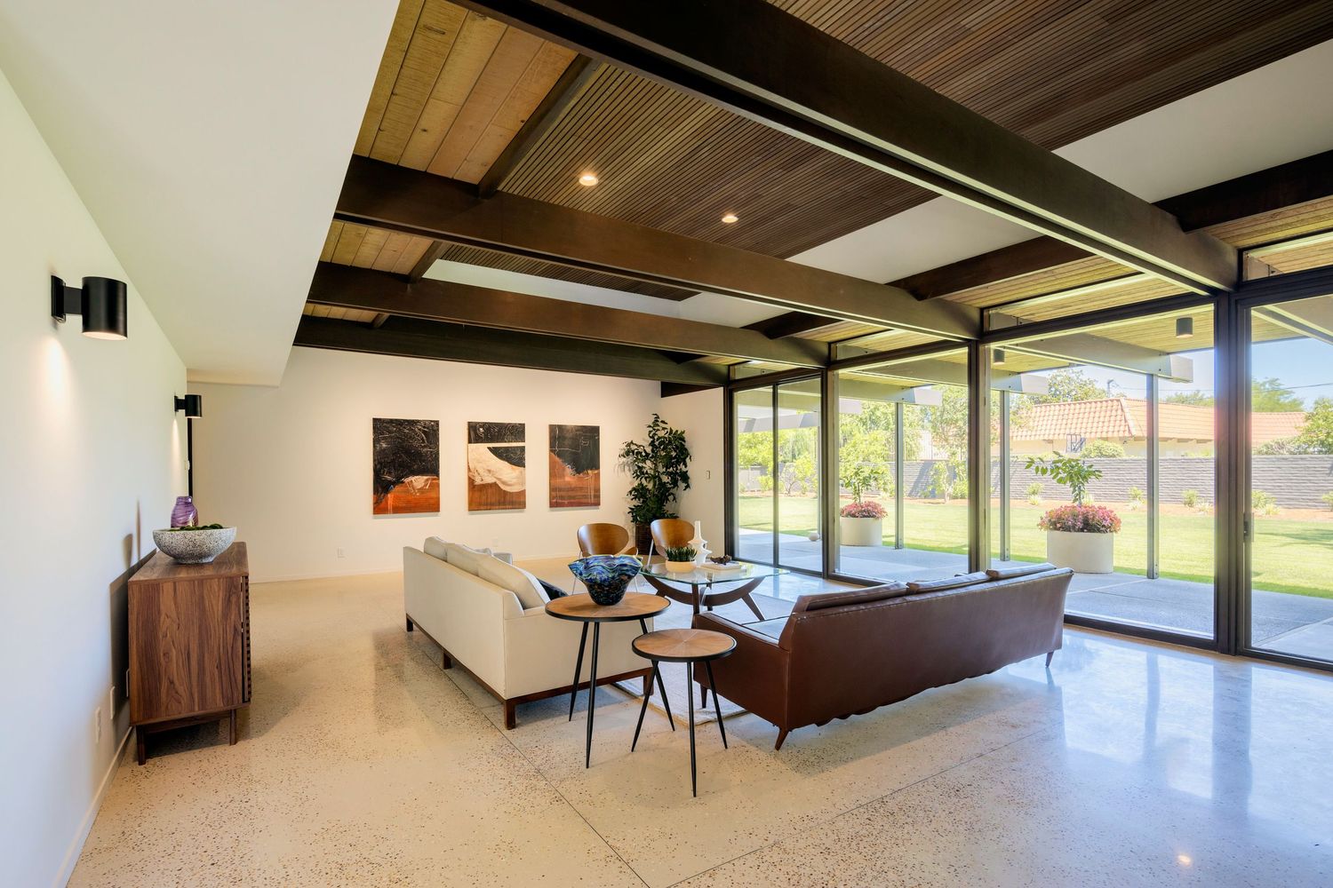 Modern home exterior with dark siding features illuminated windows and landscaping at dusk.