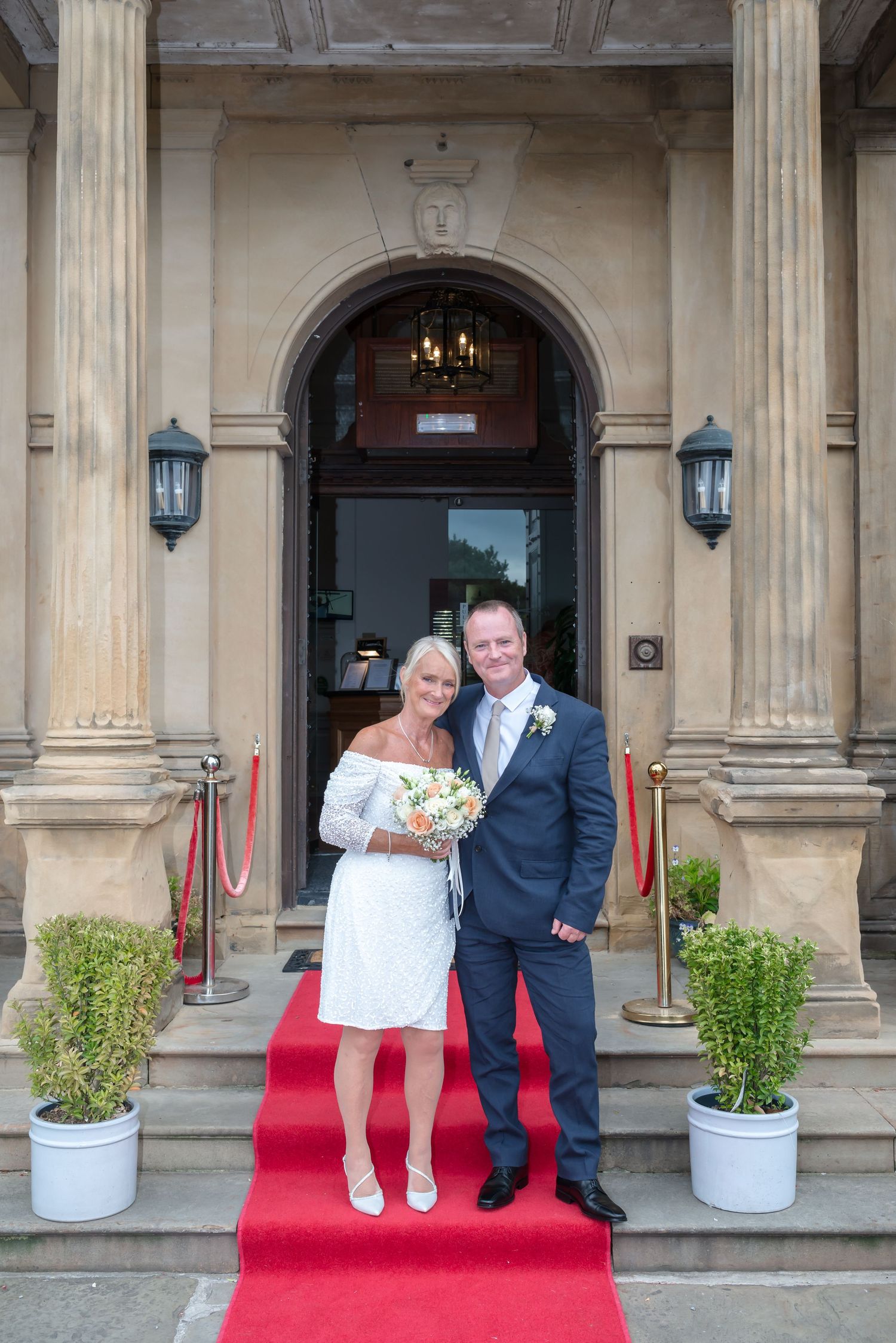 A series of wedding photos showing a couple posing on a red carpet outside an elegant building with columns.