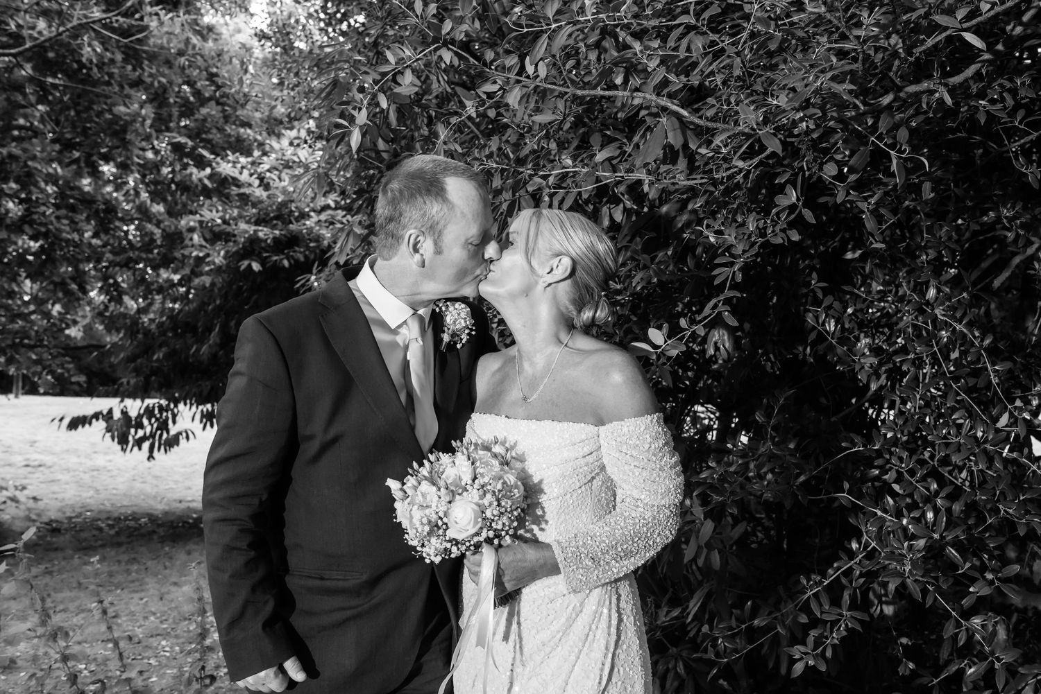 Newlyweds sharing a romantic moment in the grounds of De Vere Cranage Estate, Cheshire; candid black and white bridal photography by Michael