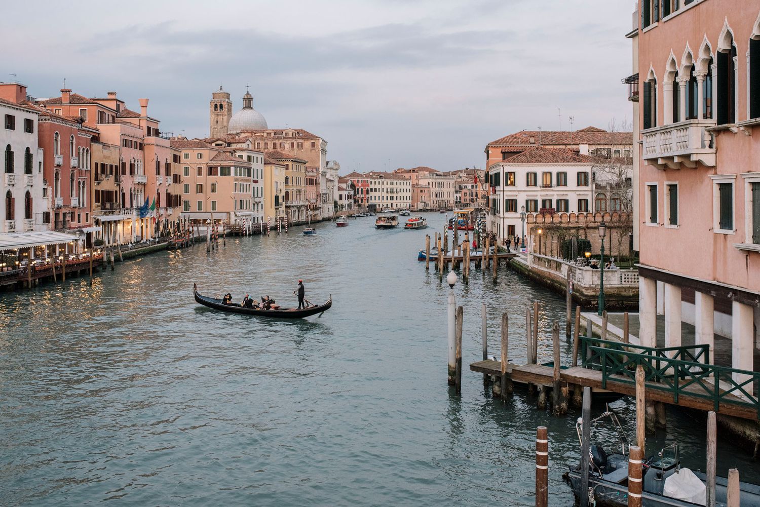Vista panoramica del Canal Grande di Venezia con le tradizionali gondole, gli edifici storici e l'architettura dai colori pastello.