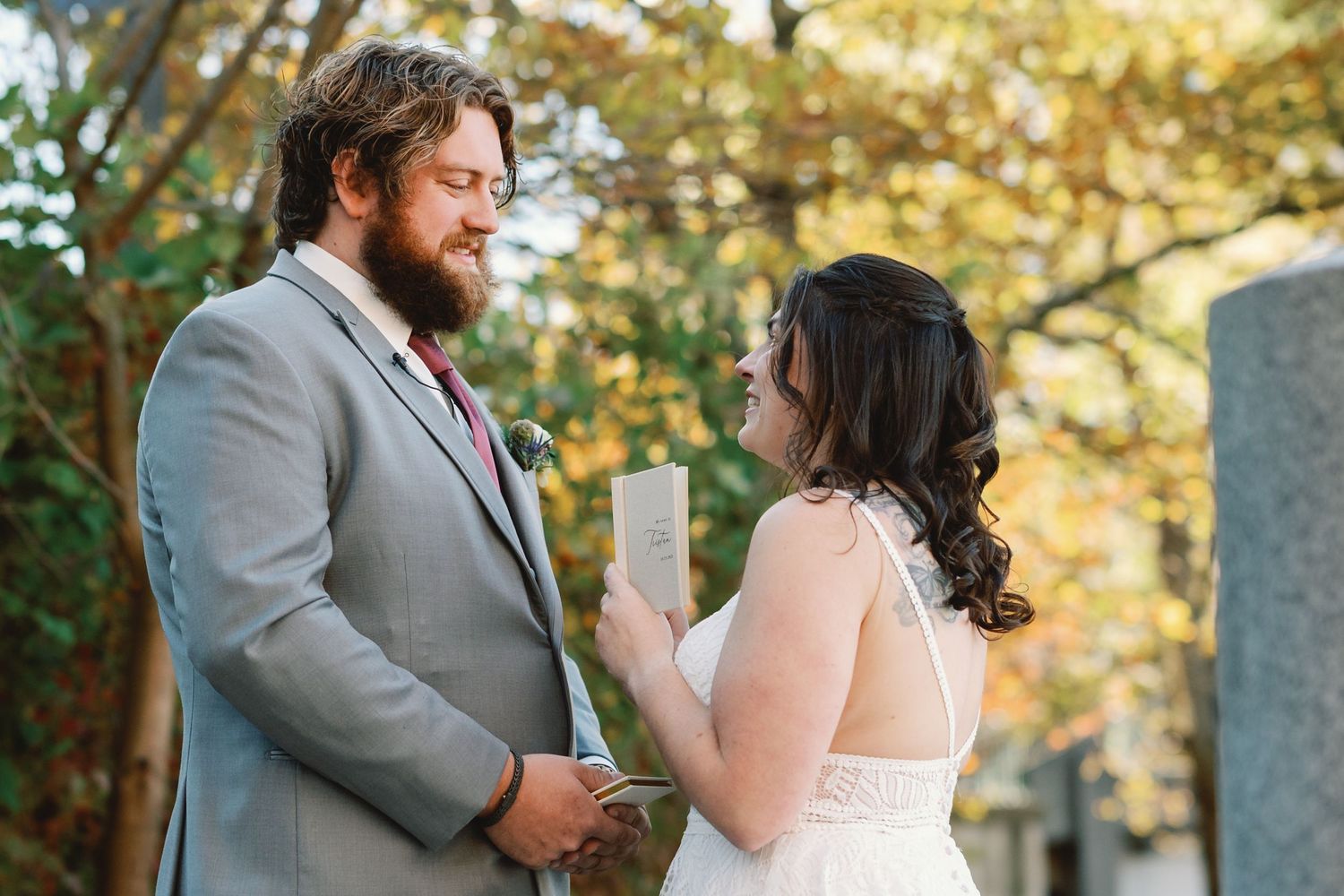 A couple shares an intimate moment during their wedding ceremony in a sunlit outdoor setting.