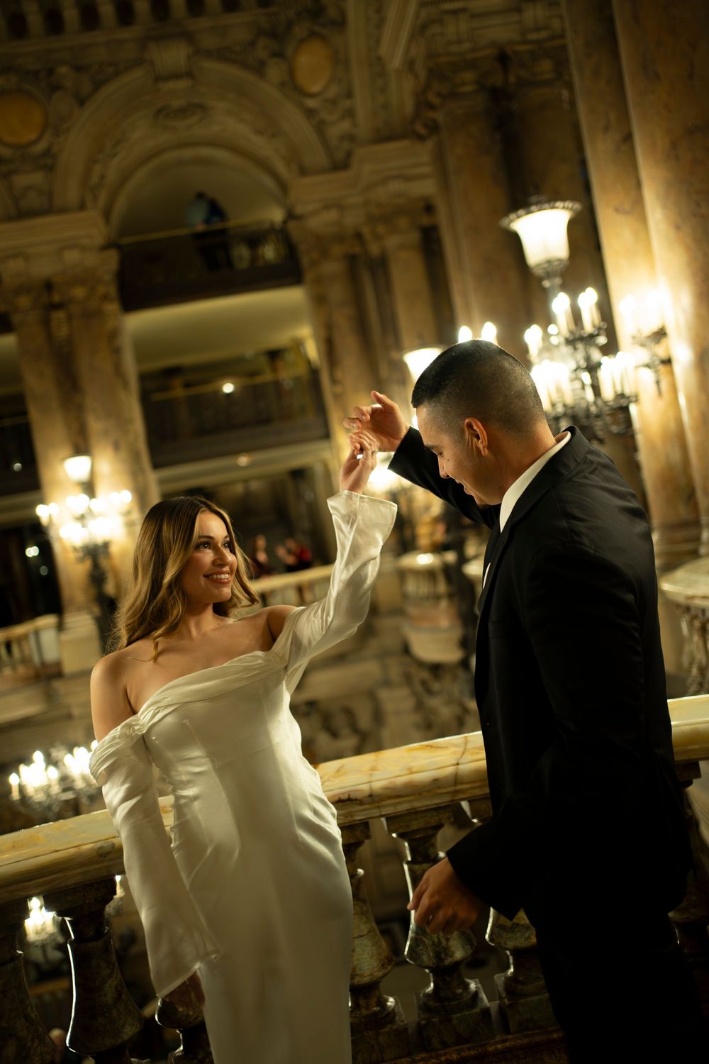 A romantic dance sequence showing a couple twirling together in an elegant ballroom with ornate lighting and decor. Paris film photography.