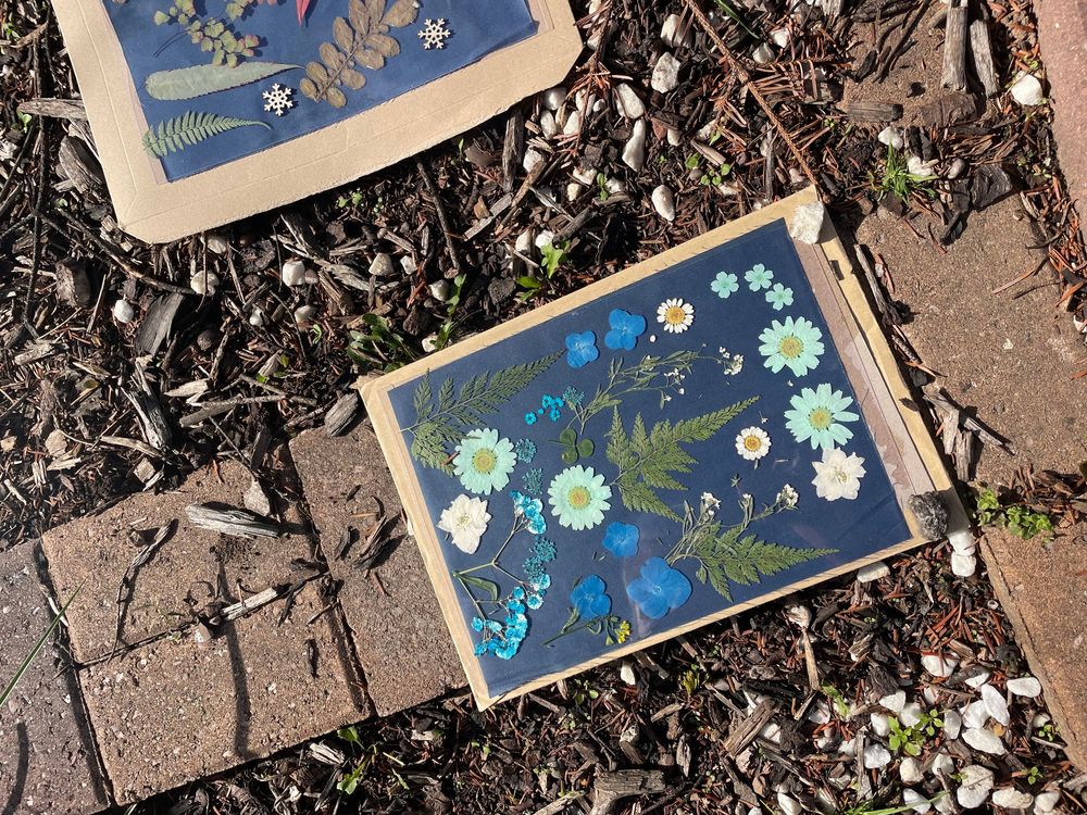 Torn paper artwork pieces with blue floral designs scattered on a dark textured ground surface.