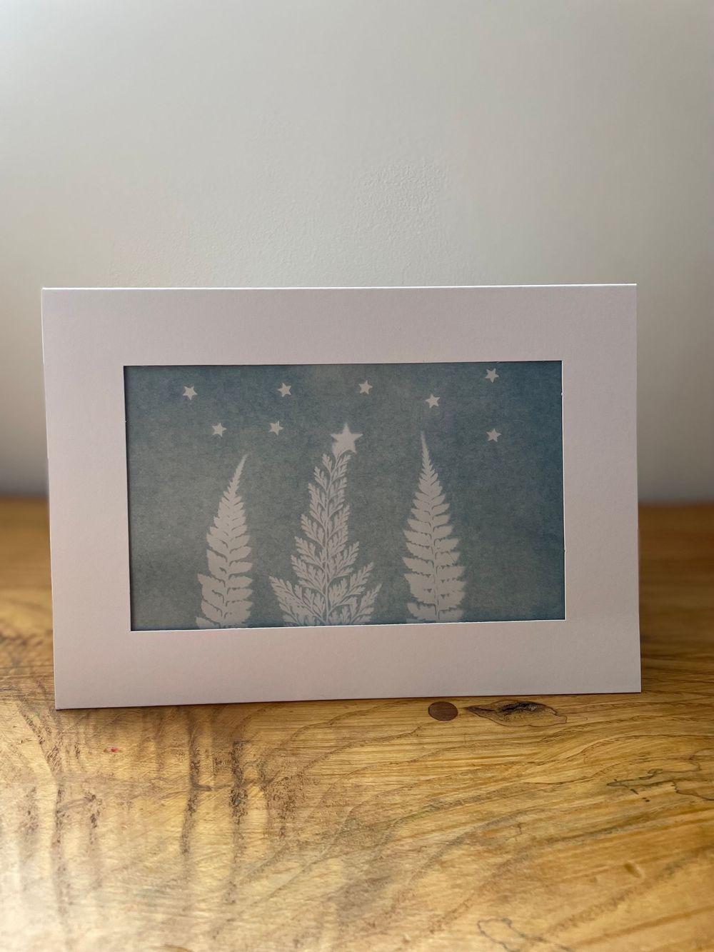 White paper cards with delicate winter forest silhouettes featuring evergreen trees and ferns on a dark teal background.