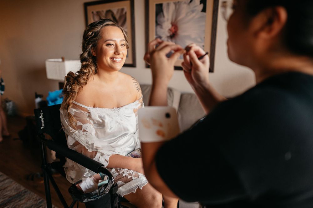 A candid moment of bridal makeup preparation in a warmly lit room.