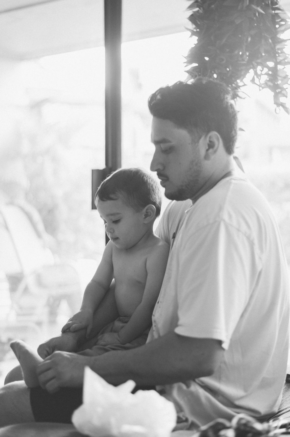 A tender black and white moment between parent and child sitting by a window.