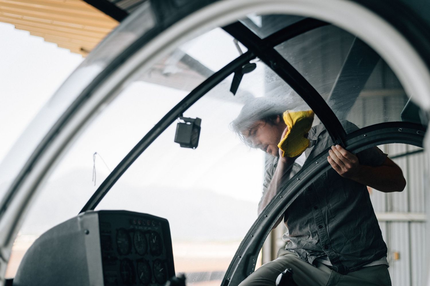 Close-up view through a helicopter cockpit window showing control panels and instruments.