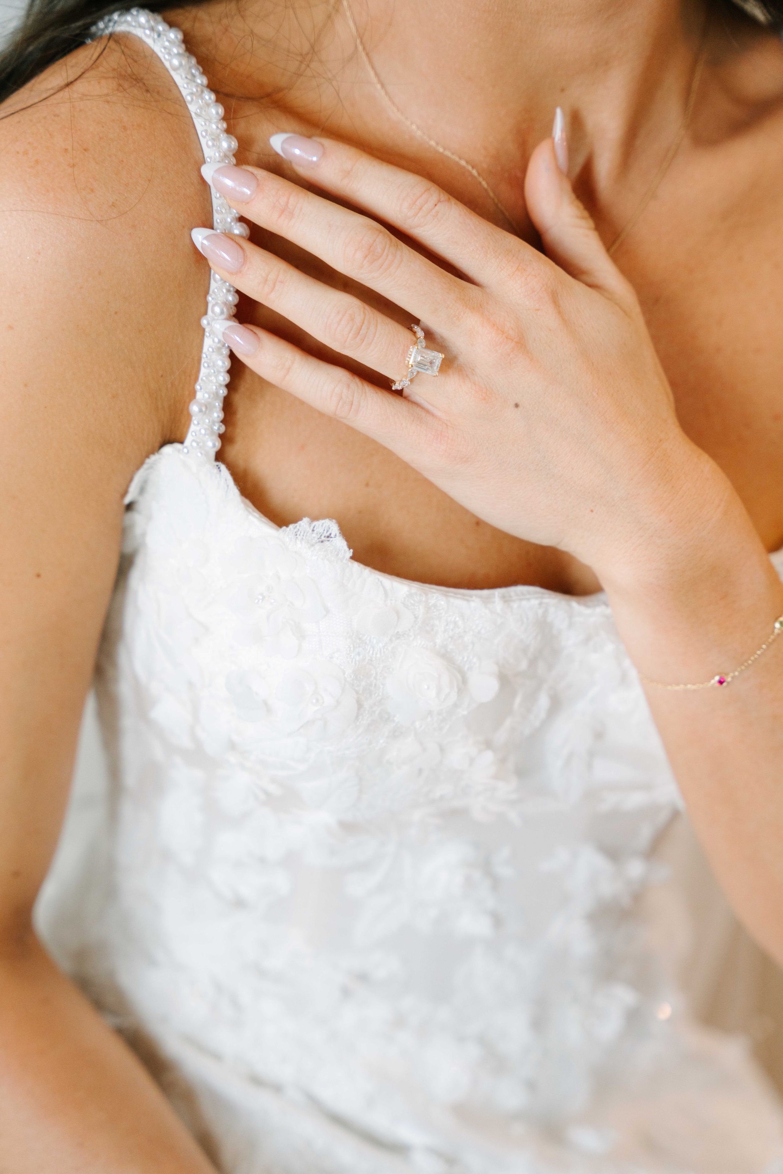 Close-up details of an elegant white wedding dress with delicate beading and lace trim.
