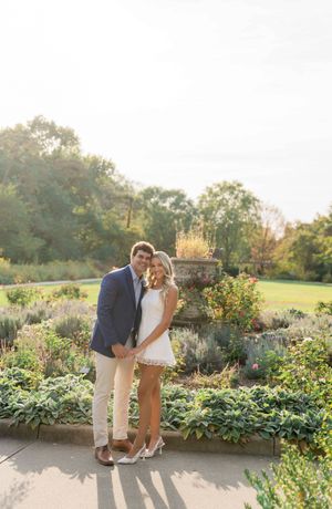 Engaged couple posing in a garden setting during golden hour with colorful flowers.