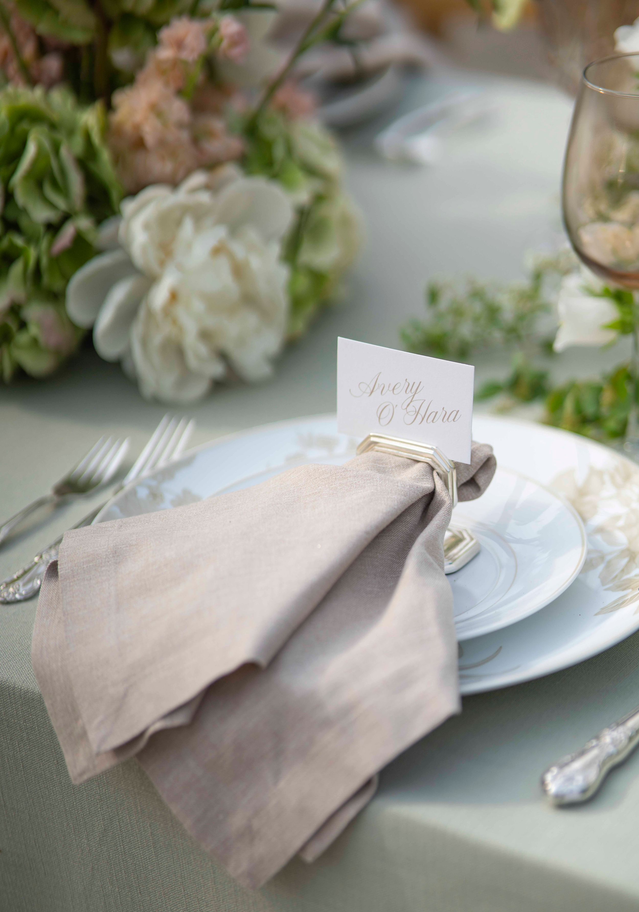 Elegant table setting with gray linen napkins and floral arrangements at a wedding reception.