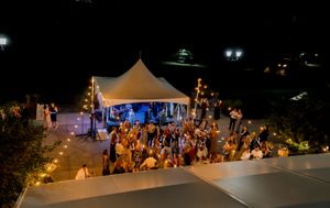 A nighttime outdoor event with illuminated tents and crowds gathering under warm lighting at a festival.