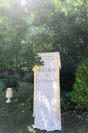 Welcome sign for a wedding displayed in a garden setting with greenery.