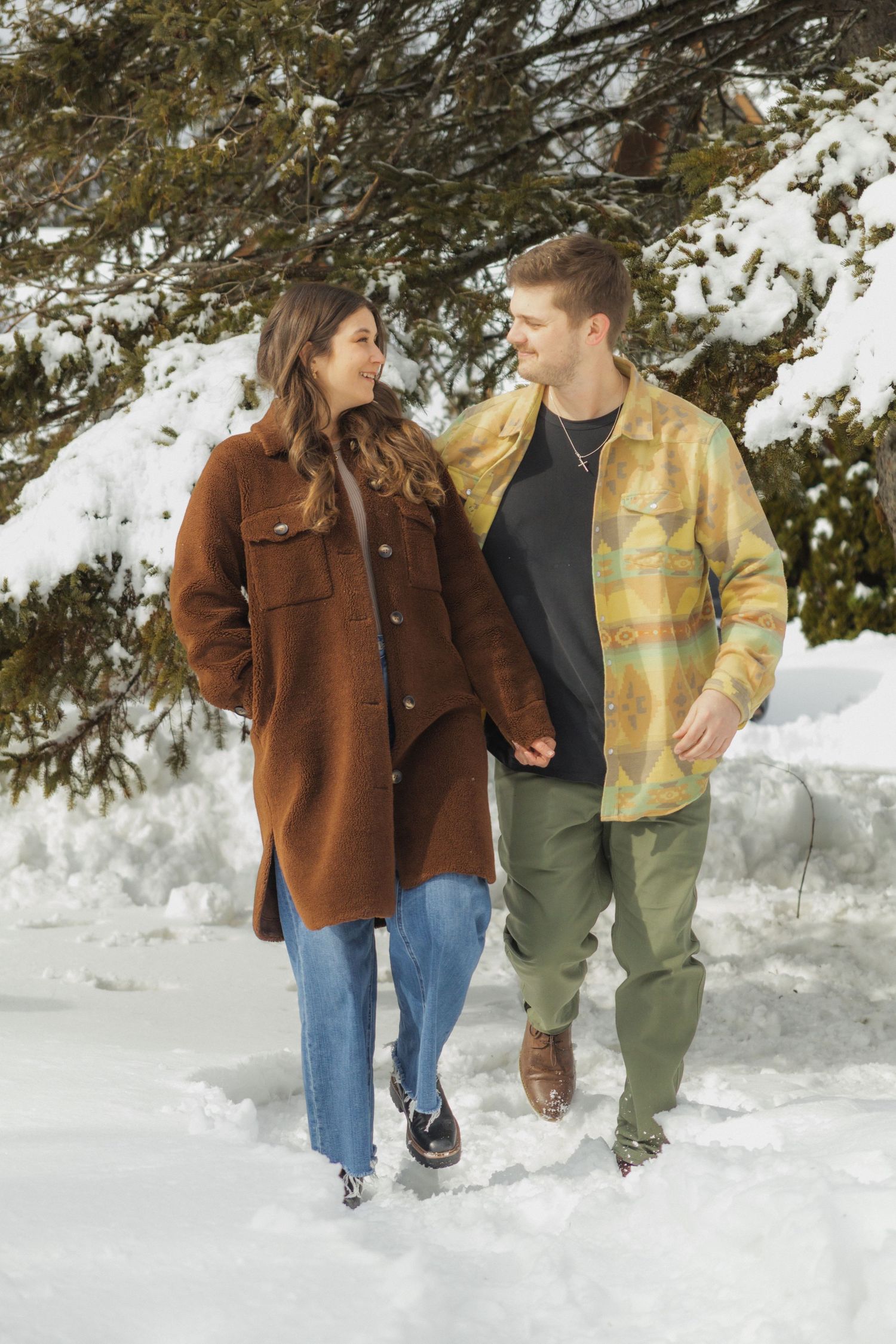 A couple standing together in a snowy woodland during an outdoor winter couples photography session.