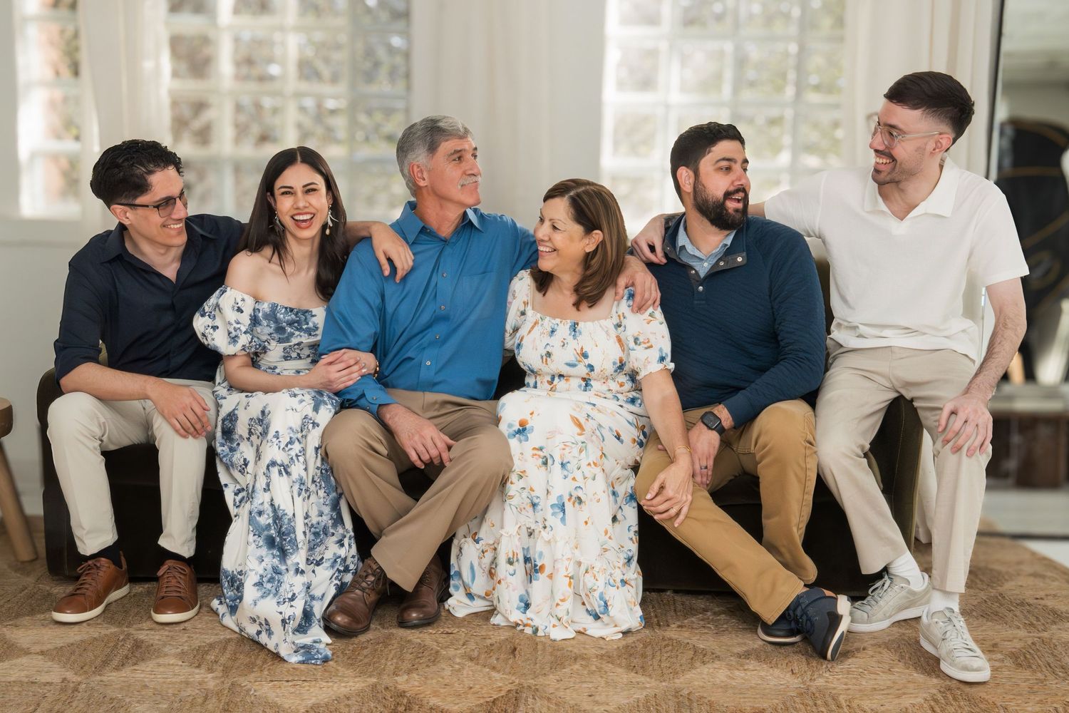 A series of coordinated family portraits showing groups wearing matching neutral and floral outfits in a bright interior setting.