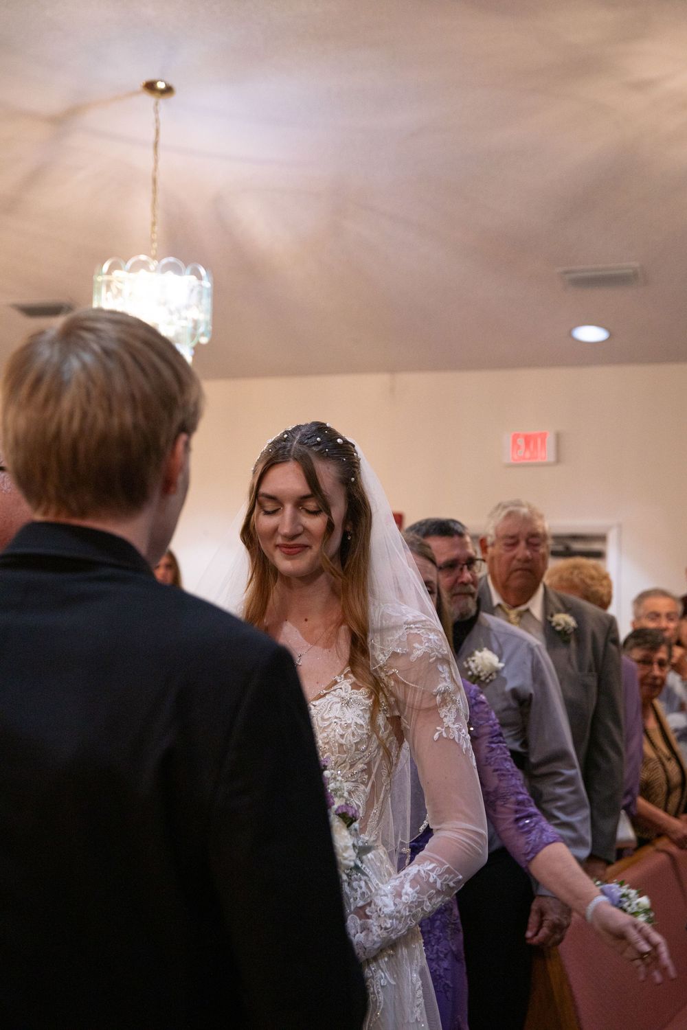 Wedding guests dance and celebrate during a reception in an elegant indoor venue with warm lighting.
