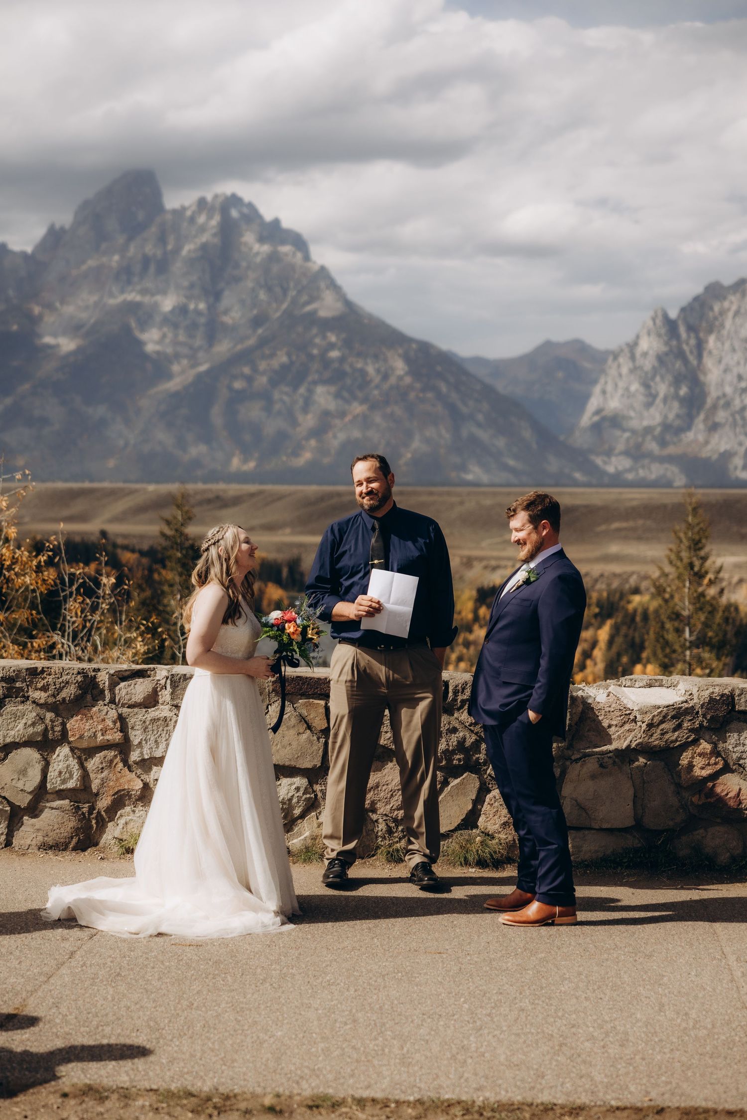 An outdoor wedding ceremony takes place against the dramatic backdrop of the Grand Teton mountains in Wyoming.