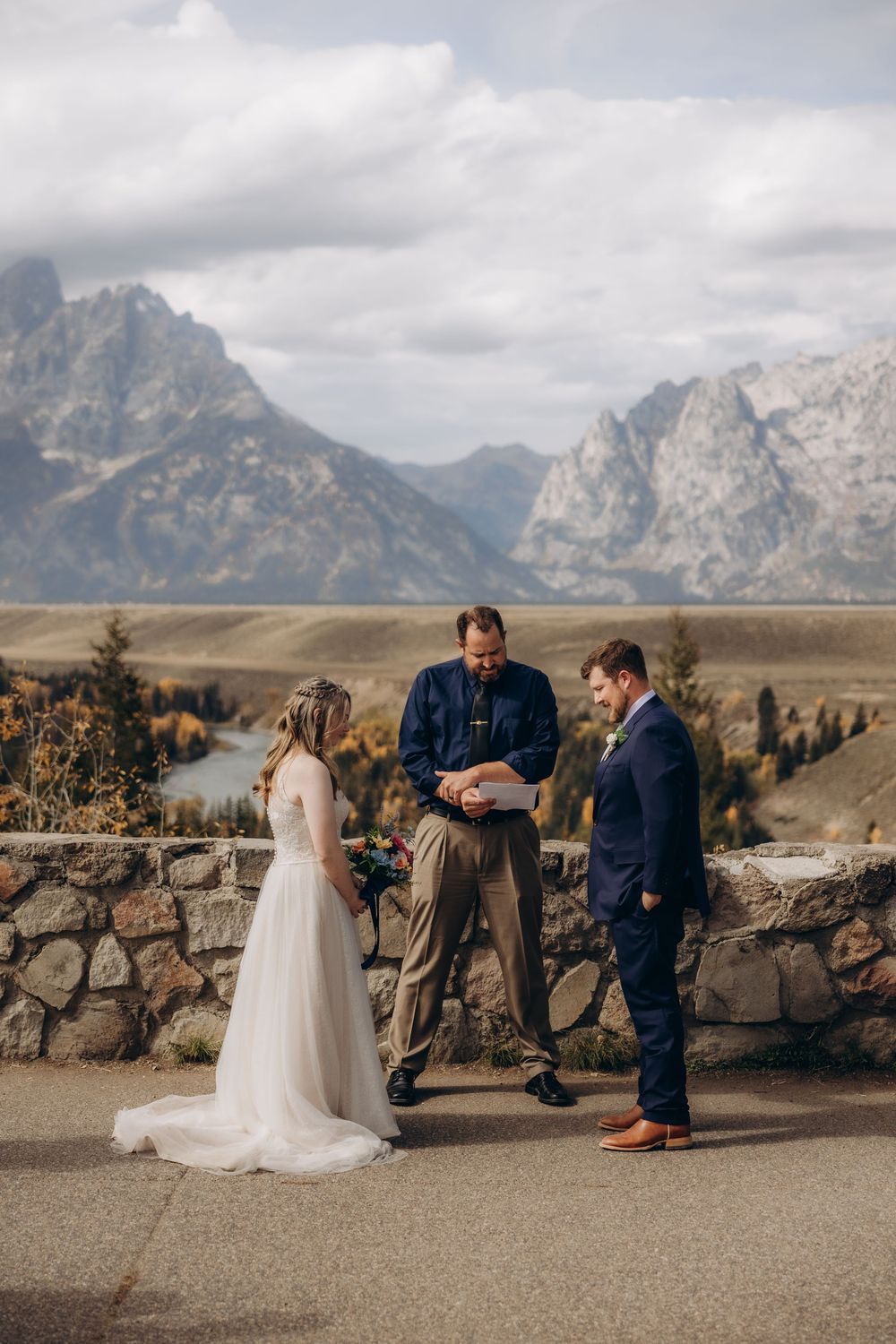 A wedding ceremony takes place against a dramatic mountain backdrop at Grand Teton National Park.