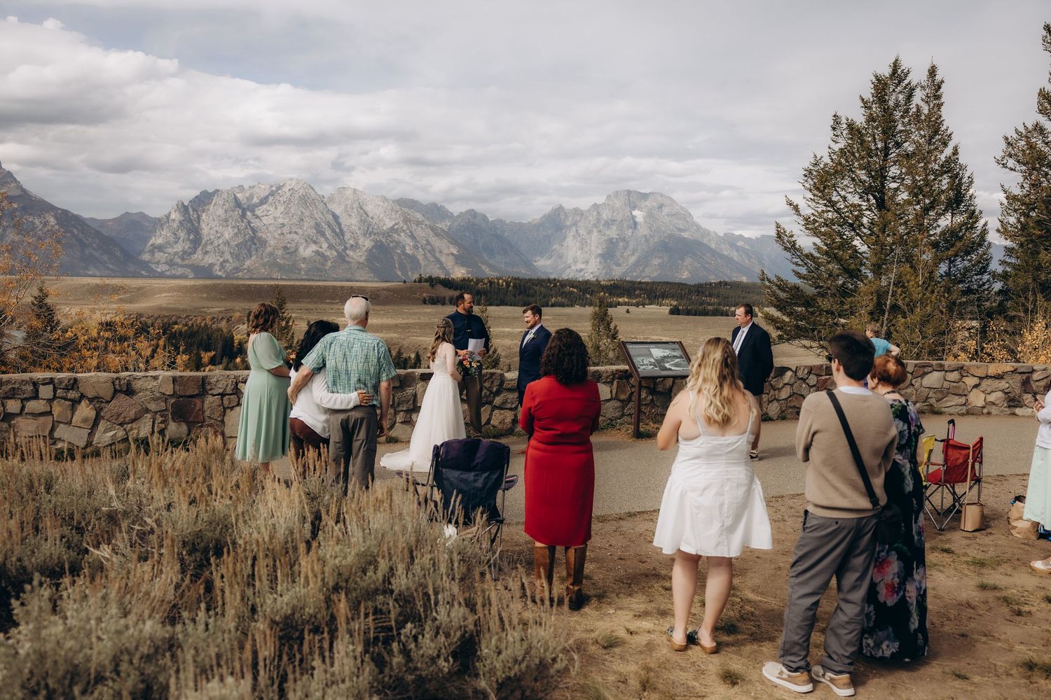 A small wedding ceremony takes place against the backdrop of majestic mountains in Grand Teton National Park.