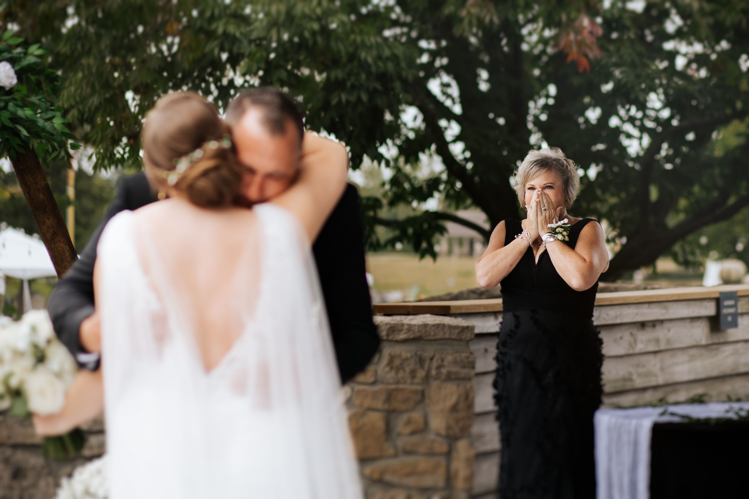 A father hugs his daughter during first look at Conner Prairie, Fishers Indiana under trees and stone walls.