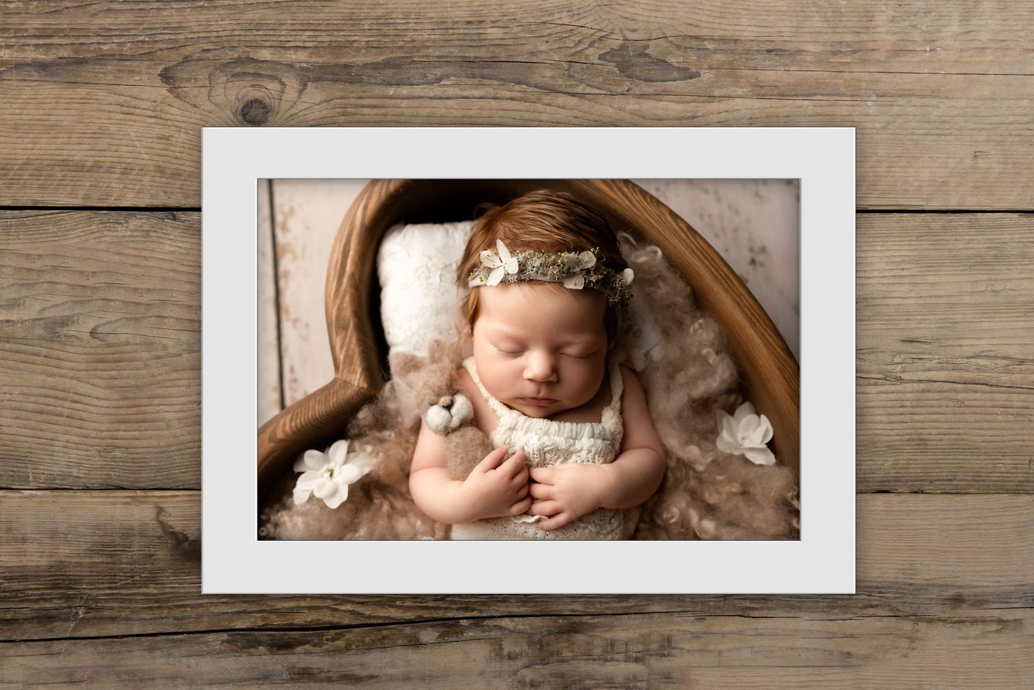 A series of sepia-toned newborn photography images displayed in white frames against a rustic wooden background.