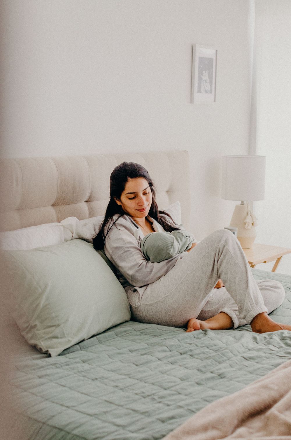 A person relaxes on a bed with mint green bedding while using a mobile device.