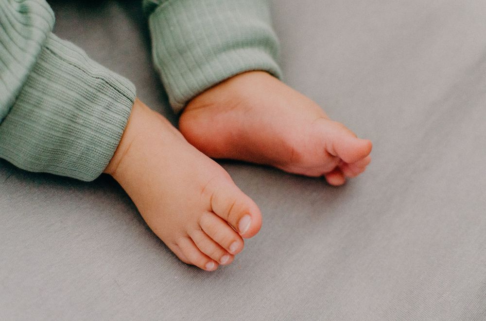 Close-up of baby's tiny feet wearing mint green ribbed clothing.