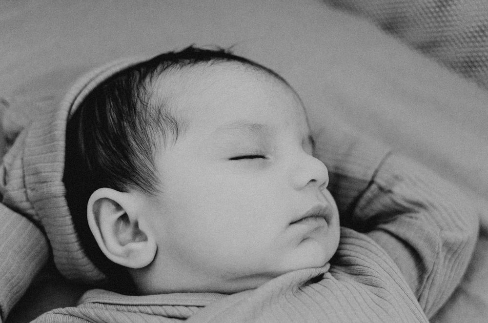 A sleeping baby rests peacefully in a cozy blanket with eyes closed.