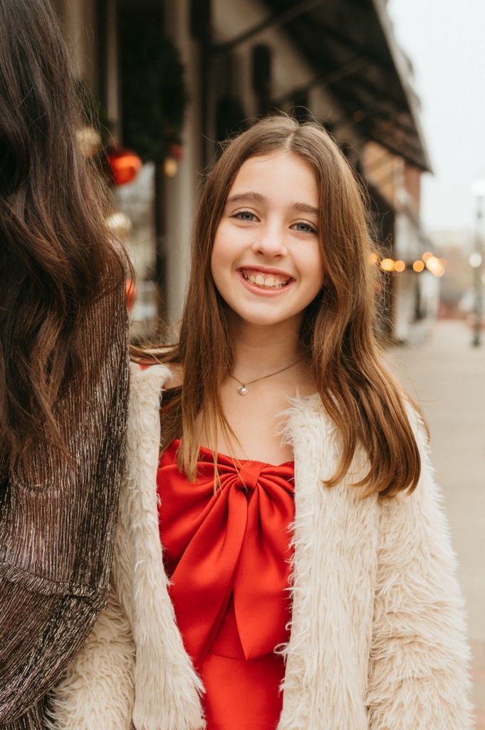 A series of portrait shots showing someone in a red top and cream colored fuzzy coat against an urban background.