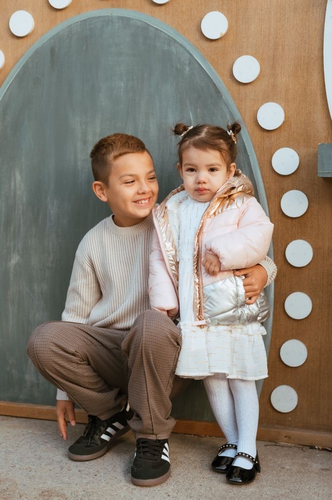 Series of tender moments between children against brown wall with white polka dot decorations.