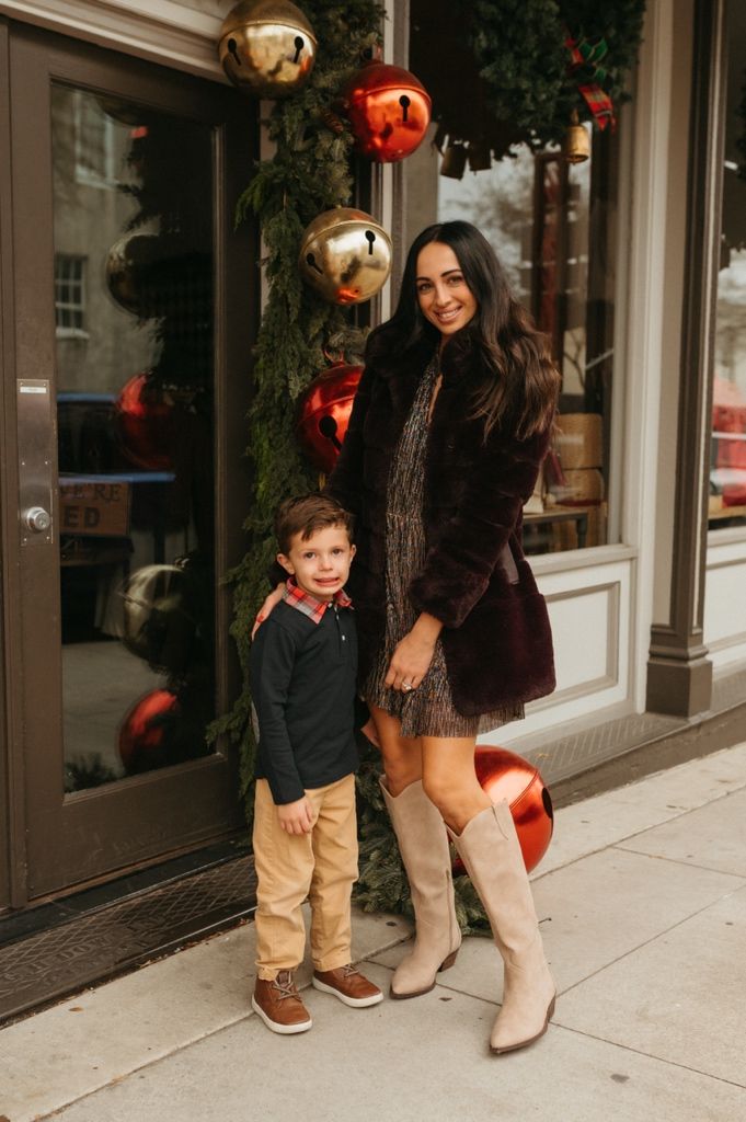 Holiday scene outside storefront with festive red and gold ornaments and greenery decorations.