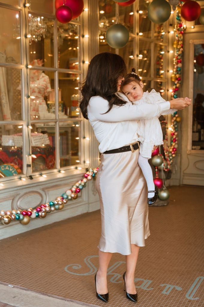 A couple dances together in a festive holiday setting with red and silver ornaments and twinkling lights.