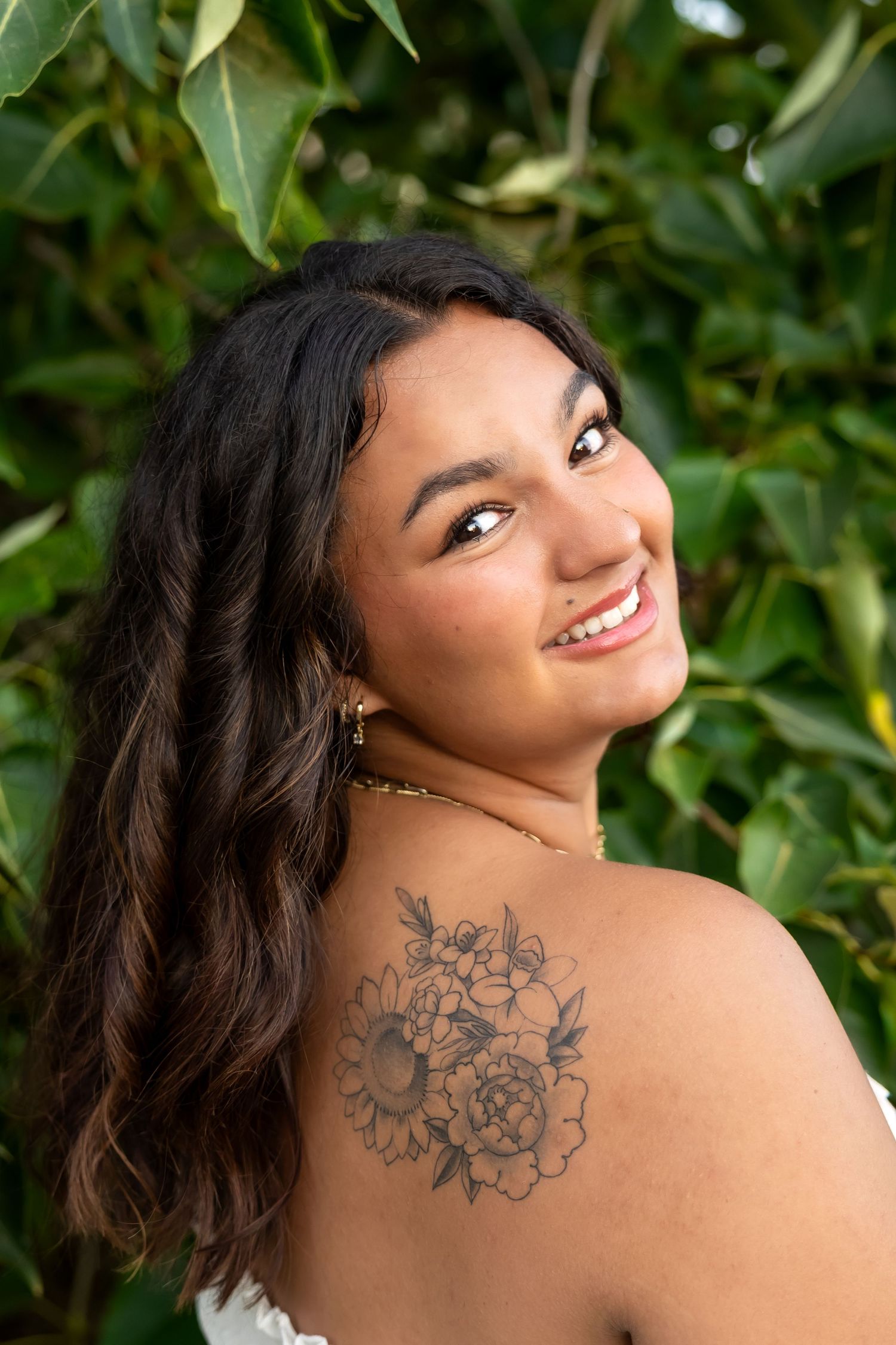 A person in a white top poses against a wooden fence during golden hour sunset in a rustic outdoor setting.