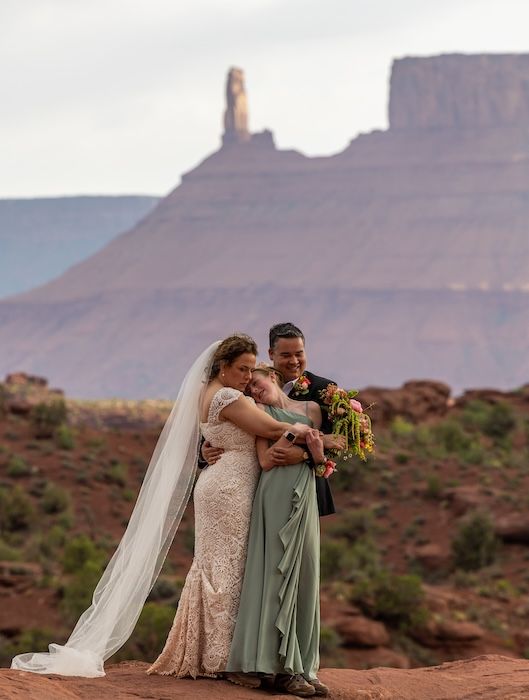 A couple shares an intimate moment during their desert wedding with towering red rock formations in Monument Valley.